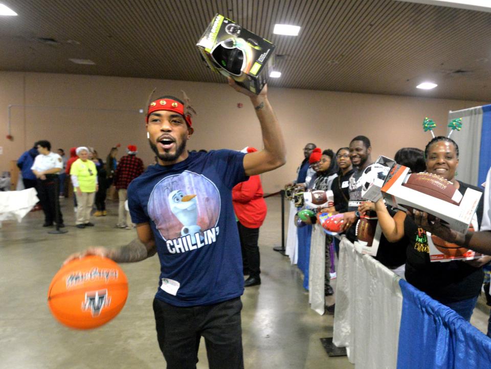 In 2019 volunteer Remain Mccreary and his co-workers from Publix call children over to their booth to receive basketballs and light-up footballs and other toys at The Children’s Christmas Party of Jacksonville