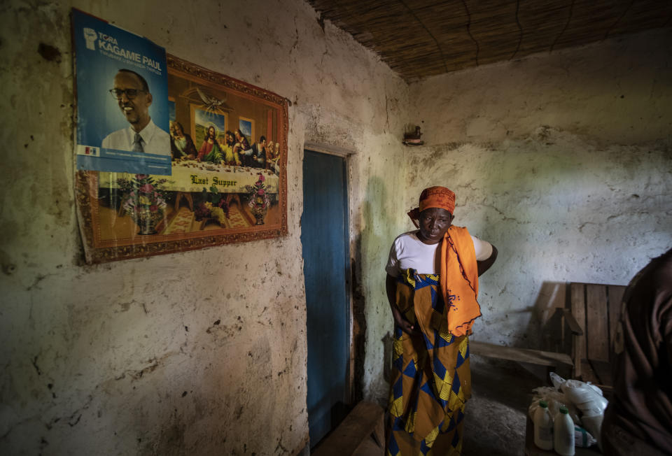 In this photo taken Tuesday, Nov. 5, 2019, Faina Nyirabaguiza, 52, who has cervical cancer, walks slowly and in pain back to her bedroom after being given an increased dose of oral liquid morphine, past posters of Christianity's The Last Supper and of Rwanda's President Paul Kagame, after a visit to check on her health by palliative care nurse Madeleine Mukantagara, at her home in the village of Ruesero, near Kibogora, in western Rwanda. While people in rich countries are dying from overuse of prescription painkillers, people in Rwanda and other poor countries are suffering from a lack of them, but Rwanda has come up with a solution to its pain crisis - it's morphine, which costs just pennies to produce and is delivered to households across the country by public health workers. (AP Photo/Ben Curtis)