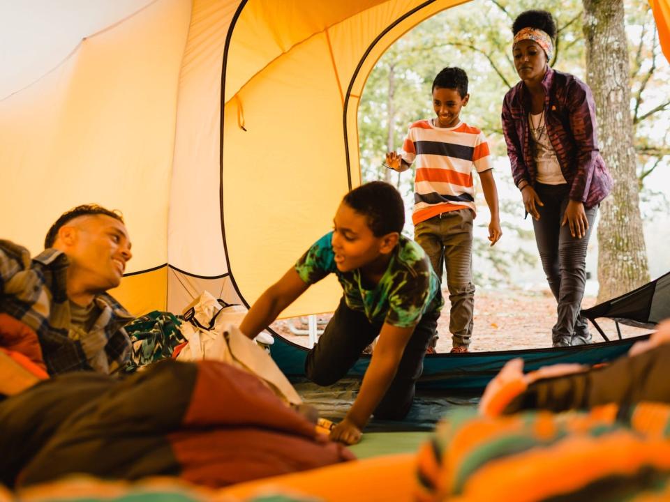 A family of four sitting in a tent at a campsite