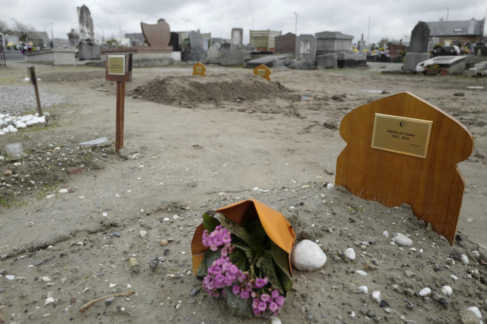 FILE- A bouquet of flower lays on the tomb of Yasser Abdallah, from Sudan, who died in an attempt to cross the English Channel in a truck on Sept. 28, 2021, in the Nord Cemetery of Calais, northern France, Thursday, Nov. 25, 2021. The price to cross the English Channel varies according to the network of smugglers, between 3,000 and 7,000 euros. Often, the fee also includes a very short-term tent rental in the windy dunes of northern France and food cooked over fires that sputter in the rain that falls for more than half the month of November in the Calais region. (AP Photo/Rafael Yaghobzadeh, File)