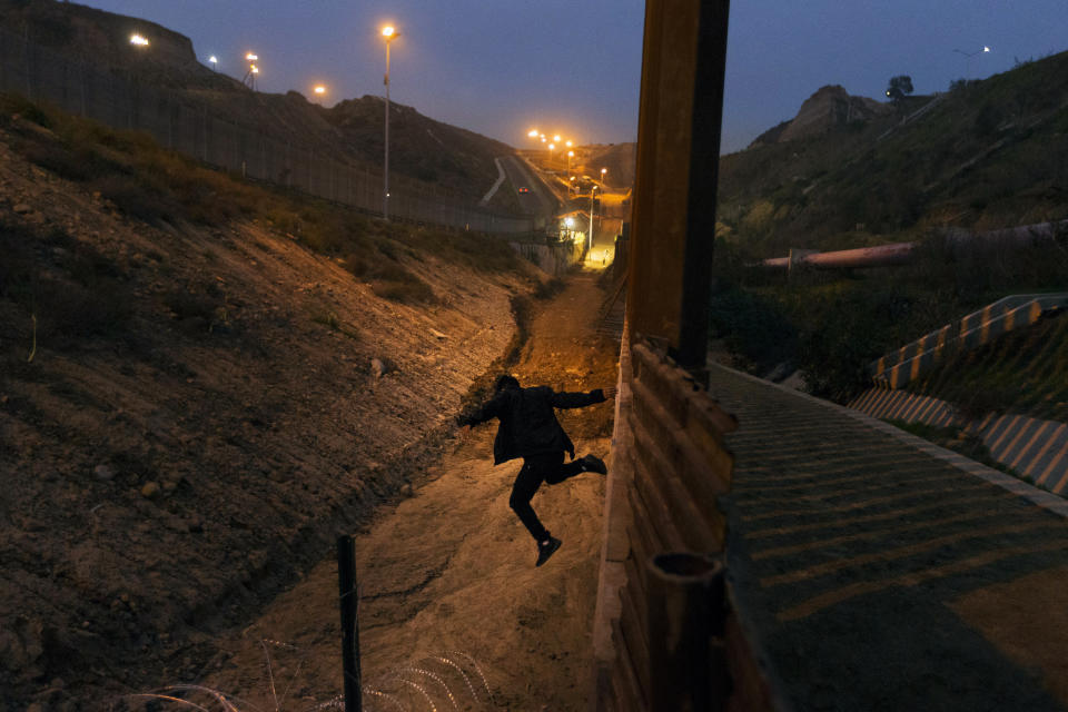 A Honduran youth jumps from the U.S. border fence, as seen from Tijuana, Mexico, on Friday, Dec. 21, 2018. Discouraged by the long wait to apply for asylum through official ports of entry, many Central American migrants from recent caravans are choosing to cross the U.S. border wall and hand themselves in to border patrol agents. (AP Photo/Daniel Ochoa de Olza)