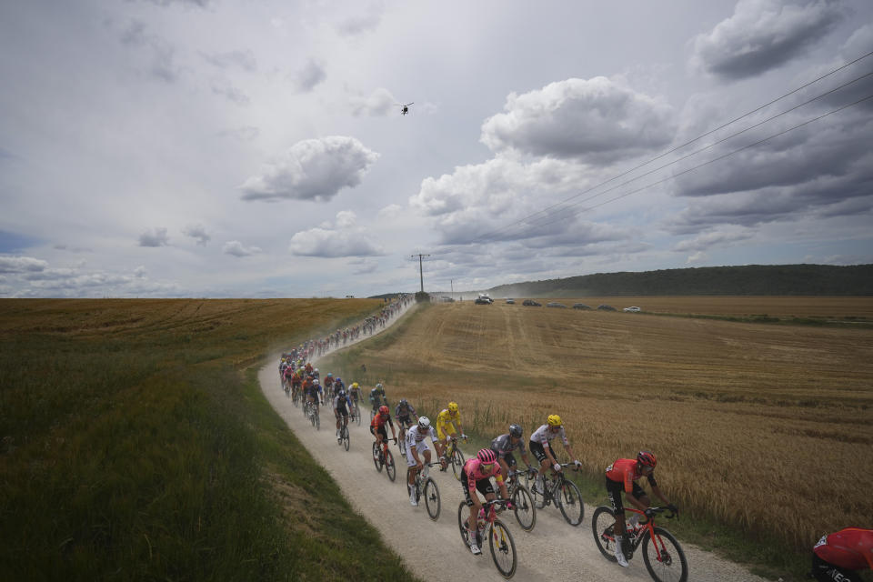 The pack with Slovenia's Tadej Pogacar, wearing the overall leader's yellow jersey, and Netherlands' Mathieu van der Poel, left of Pogacar in white, rides on a gravel road during the ninth stage of the Tour de France cycling race over 199 kilometers (123.7 miles) with start and finish in Troyes, France, Sunday, July 7, 2024. (AP Photo/Daniel Cole)