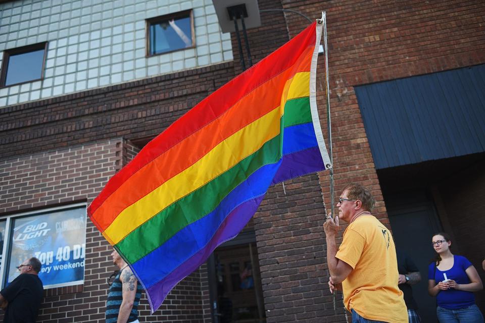 Lawrence Novotny, of Brookings, S.D., holds a rainbow-colored flag during a vigil in downtown Sioux Falls Monday, June 13, 2016, in response to the mass shooting at the Pulse nightclub in Orlando, Fla. Dozens of vigil participants marched from 11th Street and Phillips Avenue to Club David at the corner of 10th Street and Dakota Avenue in Sioux Falls. The vigil was put on by the South Dakota Peace and Justice Center and the Center for Equality. 