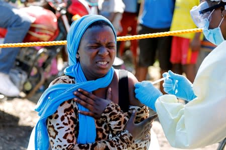 A young woman reacts as a health worker injects her with the Ebola vaccine, in Goma