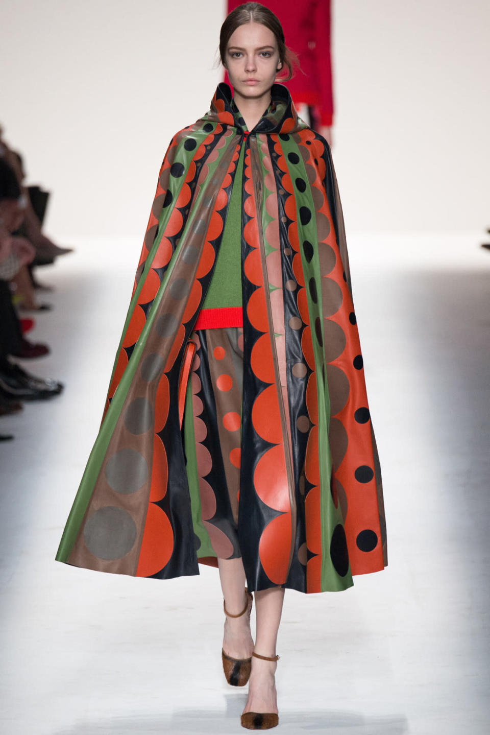 A model in a red, green, black, and brown ensemble on the runway during Valentino’s Fall 2014 show. 