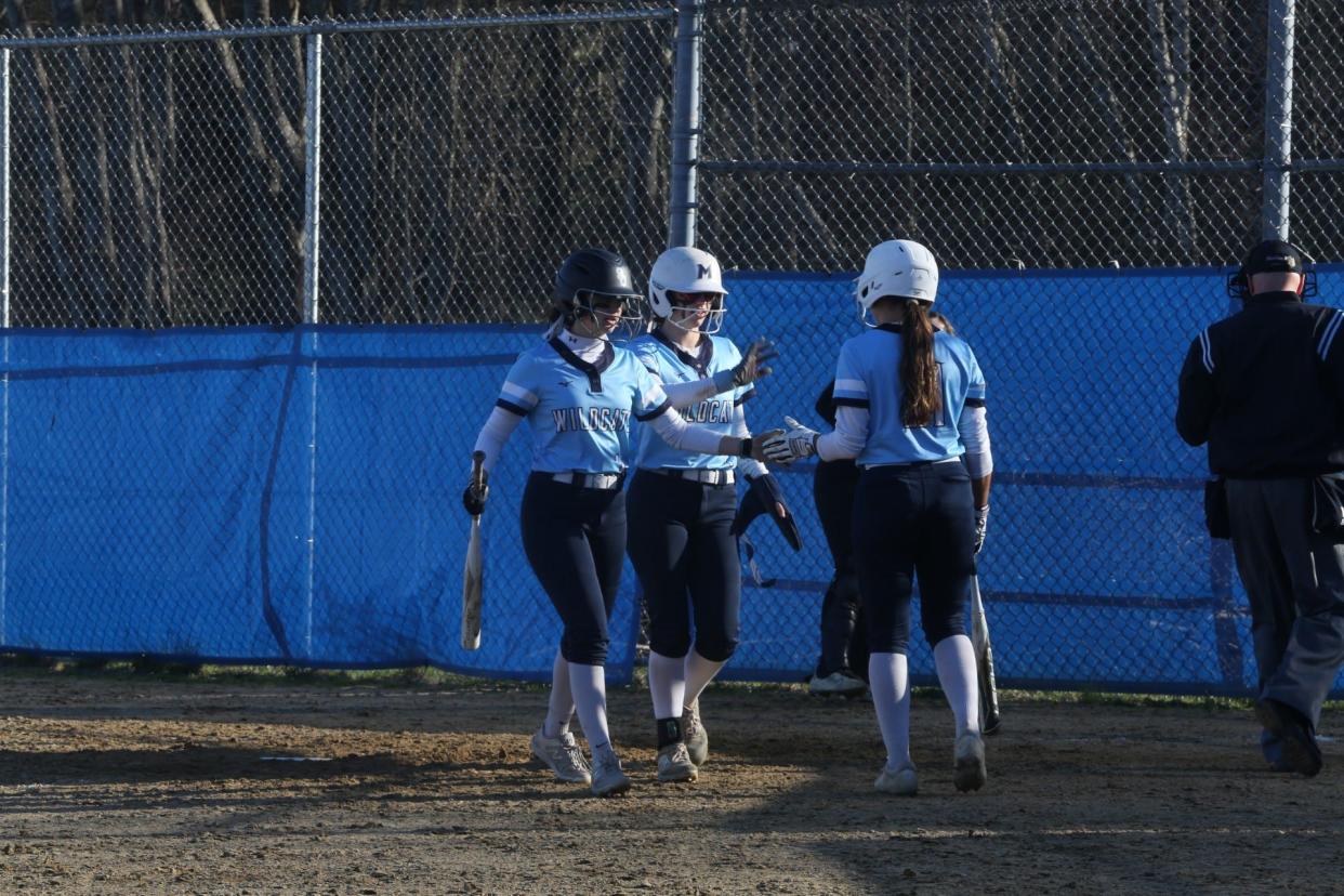 York's Bella Santini (21) greets teammates Emily Estes and Maddie Fitzgerald at home plate after Estes and Fitzgerald scored in the fifth inning in York's 10-0 win over Wells.