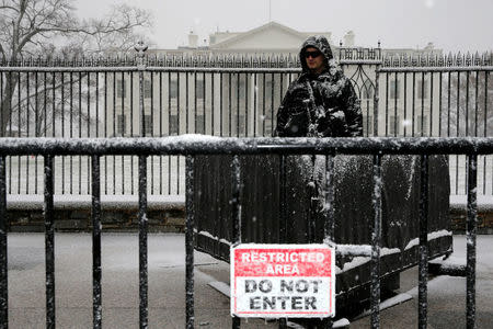 A U.S. Secret Service police officer stands watch as light snow falls in front of the White House in Washington, U.S. March 21, 2018. REUTERS/Jonathan Ernst