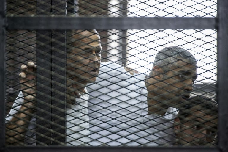 Al-Jazeera journalists Peter Greste (L), Mohamed Fadel Fahmy (C) and Baher Mohamed listen to the verdict from the defendants cage during their initial trial in June 2014 in Cairo