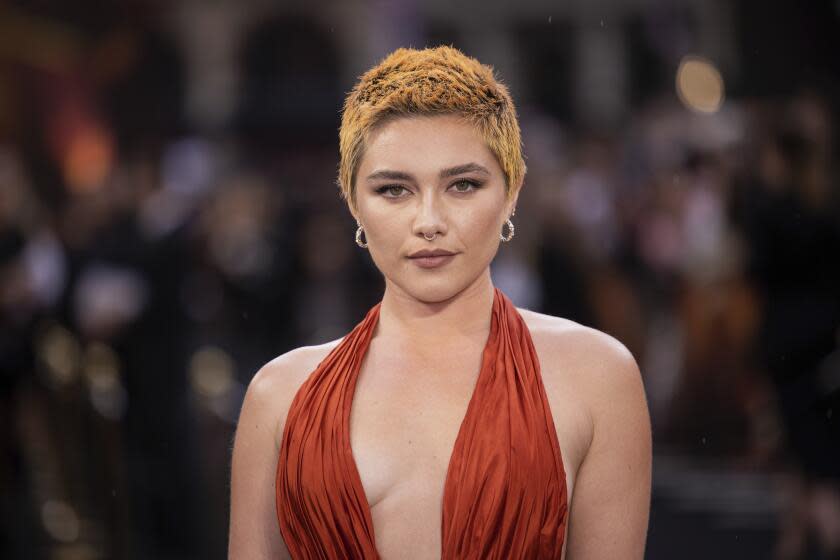 Florence Pugh poses in a red dress with a plunging neckline.