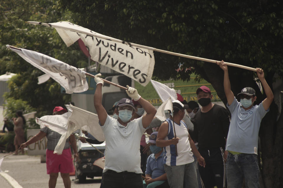 La gente levanta banderas blancas para pedir comida a los autos que pasan por la Carretera de Oro en Ilopango, El Salvador, el martes 19 de mayo de 2020. (AP Foto/Salvador Melendez)