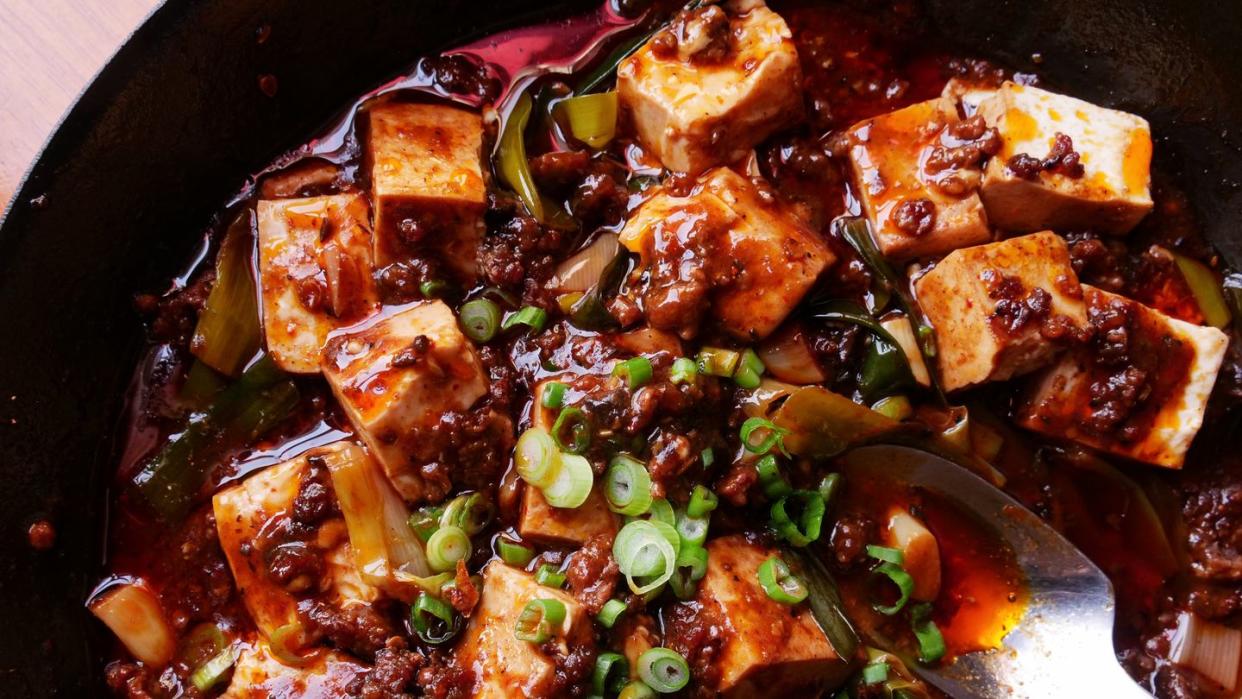 red oil surrounds shiny cubes of flavorful soft tofu sprinkled with sesame and scallions
