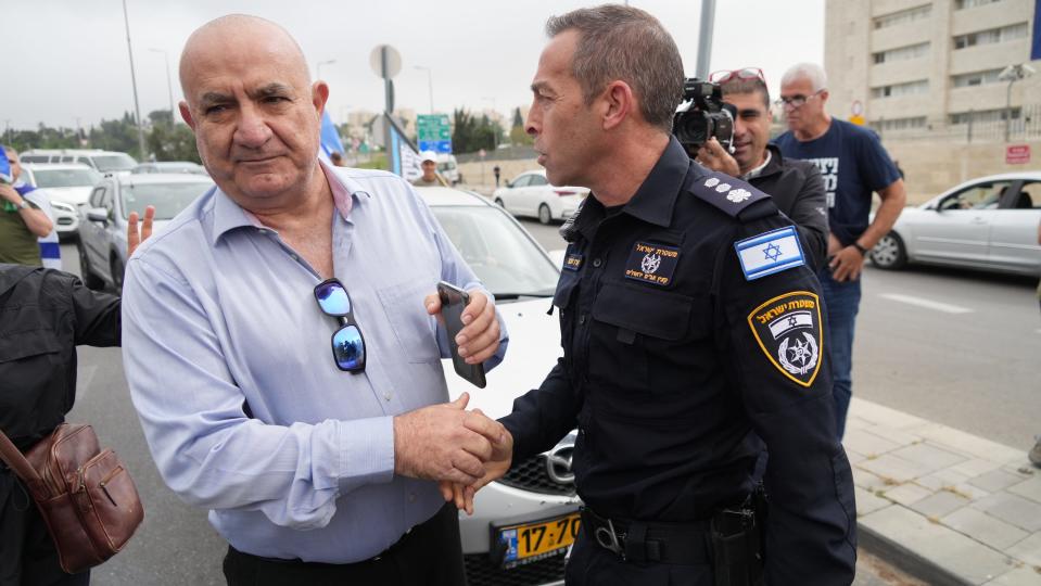 Former Israeli National Police Commissioner Moshe Karadi, left, shakes the hand of a police officer at a protest in Jerusalem on April 20, 2023.