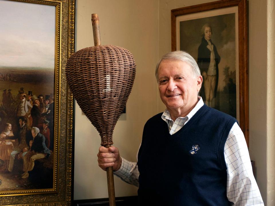 Robert Hansen holds an antique wicker basket hole marker at the Old Golf Shop.