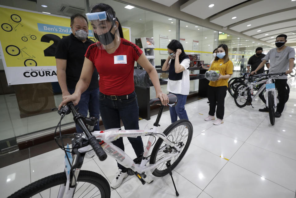 Benjamin Canlas Courage to be Kind Foundation founder Dr. George Canlas, left, looks at a recipient pushing a bicycle during ceremonies at the financial district of Manila, Philippines, Saturday, July 11, 2020. Restricted public transportation during the lockdown left many Filipinos walking for hours just to reach their jobs. The foundation saw the need and gave away mountain bikes to nominated individuals who are struggling to hold on to their jobs in a country hard hit by the coronavirus. (AP Photo/Aaron Favila)