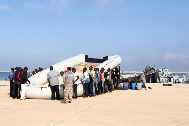 Migrants carry a raft, after being rescued by the Libyan coastguard, at a naval base near the capital Tripoli on October 5, 2015