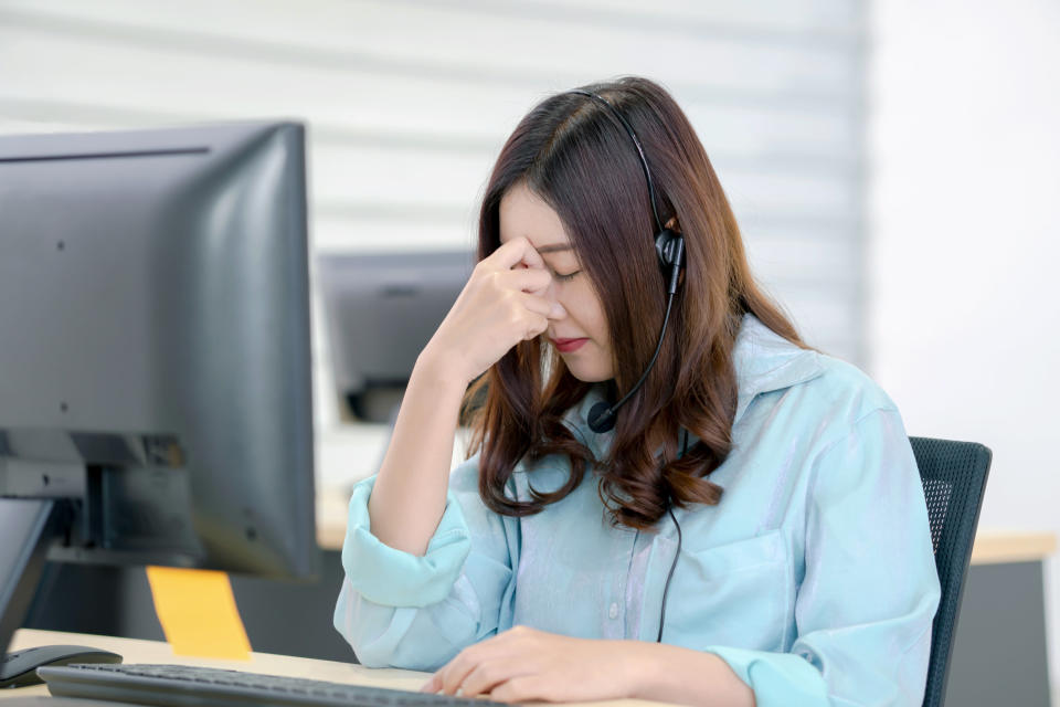 woman looking annoyed while on a call at a call center