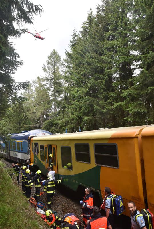Rescuers and firefighters are seen working on a site of a train crash near Pernink