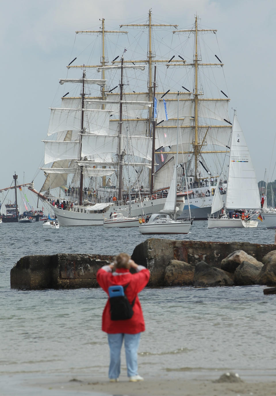 A woman watches the Windjammer Parade of tall ships on June 23, 2012 in Kiel, Germany. The parade, which features approximately 100 tall ships and traditional large sailing ships, is the highlight of the Kieler Woche annual sailing festival, which this year is celebrating its 130th anniversary and runs from June 16-24. (Photo by Sean Gallup/Getty Images)