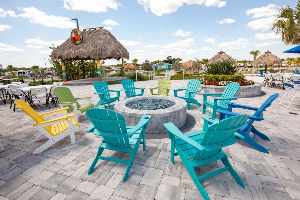 Lounge chairs surrounding a fire pit in front of a roof with a thatched pattern.