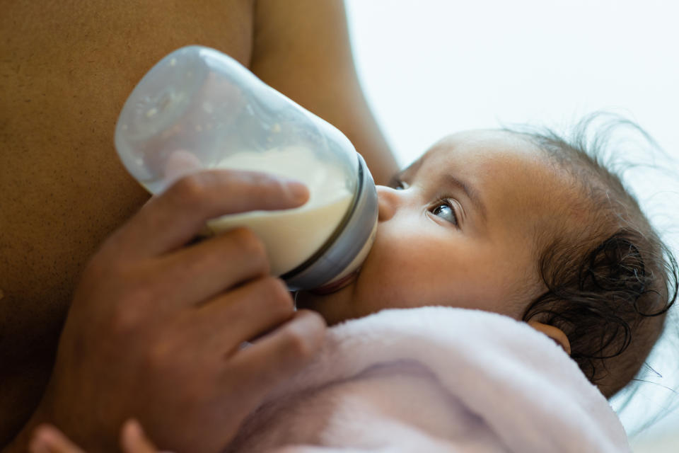 Infant being bottle-fed by a caregiver, close-up view, baby's eyes gazing upward