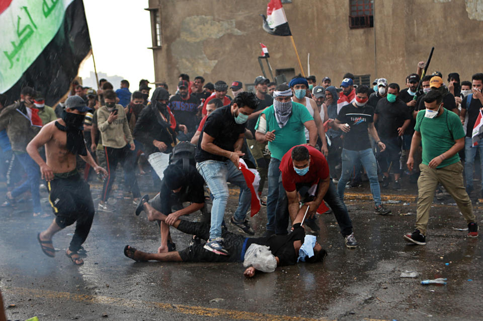 An injured protestor is rushed to a hospital during a demonstration in central Baghdad, Iraq, Friday, Oct. 25, 2019. Iraqi police fired live shots into the air as well as rubber bullets and dozens of tear gas canisters on Friday to disperse thousands of protesters on the streets of Baghdad, sending young demonstrators running for cover and enveloping a main bridge in the capital with thick white smoke. (AP Photo/Khalid Mohammed)