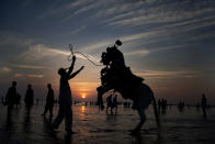 <p>Adnan Khan directs his horse to perform in an attempt to attract people visiting Clifton beach in Karachi, Pakistan, Nov. 14, 2014. Khan earns his living by providing the horse ride to customers visiting a beach. (AP Photo/Shakil Adil) </p>