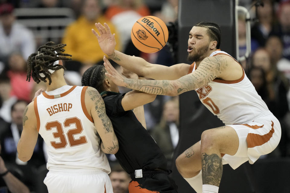 Miami guard Isaiah Wong drives to the basket between Texas forward Christian Bishop (32) and forward Timmy Allen in the first half of an Elite 8 college basketball game in the Midwest Regional of the NCAA Tournament Sunday, March 26, 2023, in Kansas City, Mo. (AP Photo/Charlie Riedel)