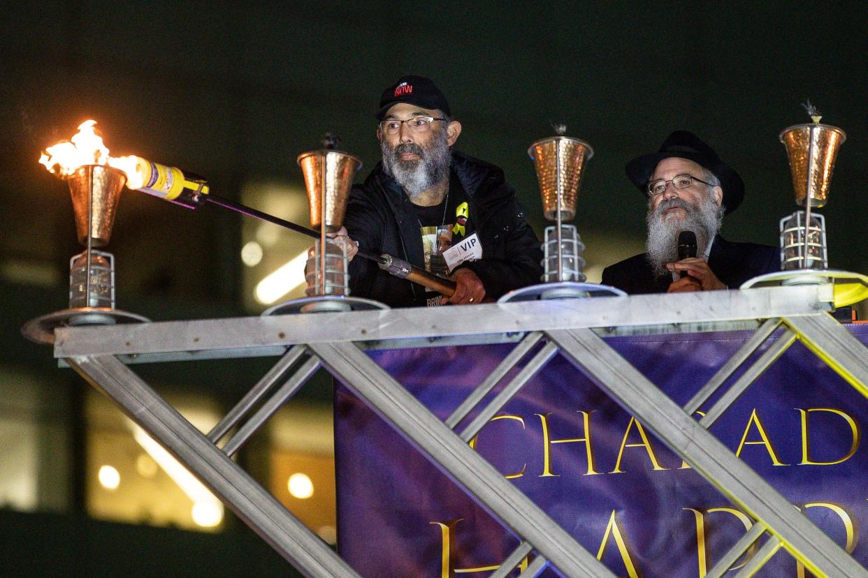 Yair Moses Finkelstein, whose father Gadi Moses is held hostage by Hamas lights up the first candle during the annual Menorah in the D at Campus Martius in Detroit on Thursday, Dec. 7, 2023.