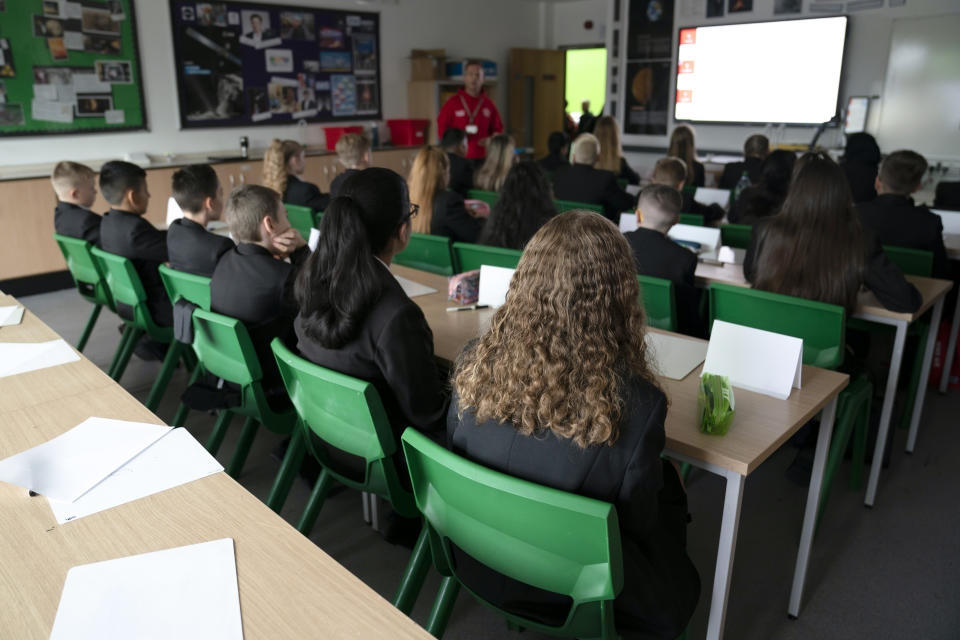 FILE - In this Sept. 3, 2021, file photo, year 7 students arrive back at Great Academy Ashton in Manchester as schools reopen after the summer holidays, Ashton-Under-Lyne, England. Pupils and teachers in England's schools don't have to wear face coverings, despite the objections of unions and public health officials — a contrast to European countries including France, Italy and Spain that have kept mask requirements for schools. (AP Photo/Jon Super, File)