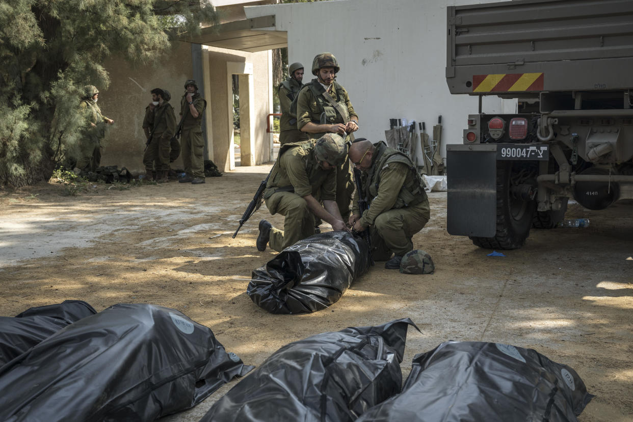 Soldados israelíes cerca de casas destruidas en Kfar Aza, un poblado ubicado justo al cruzar la frontera de Gaza, el cual fue atacado por hombres palestinos armados, en Israel, el martes 10 de octubre de 2023. (Sergey Ponomarev/The New York Times)