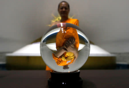 A Buddhist monk from the Wat Phra Dhammakaya temple is seen reflected in a crystal ball inside of the golden statue chamber as the Department of Special Investigation (DSI) officers inspect the temple, in Pathum Thani province, Thailand March 10, 2017. REUTERS/Jorge Silva