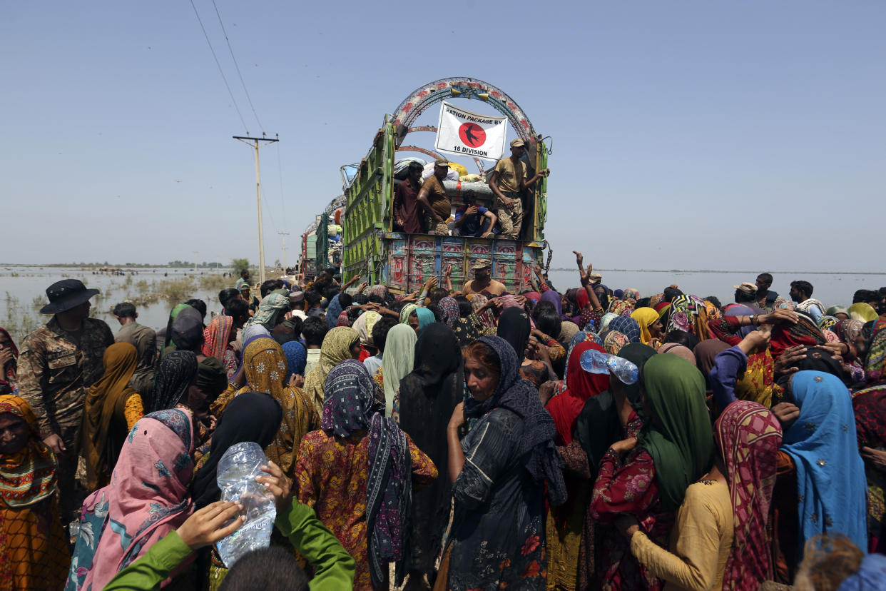 Victims of heavy flooding from monsoon rains gather to receive relief aid from the Pakistani Army in the Qambar Shahdadkot district of Sindh Province, Pakistan, Friday, Sept. 9, 2022. U.N. Secretary-General Antonio Guterres appealed to the world for help for cash-strapped Pakistan after arriving in the country Friday to see the climate-induced devastation from months of deadly record floods. (AP Photo/Fareed Khan)