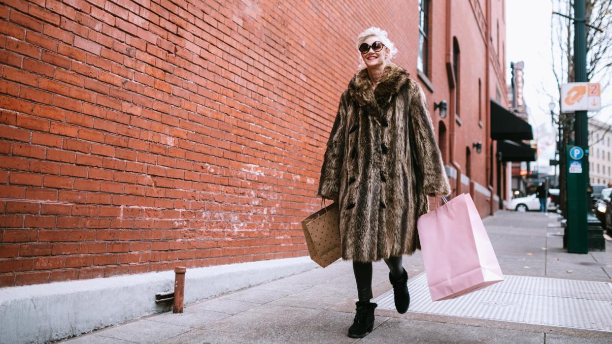  Woman carrying shopping bags past a shop window in the boxing day sales. 