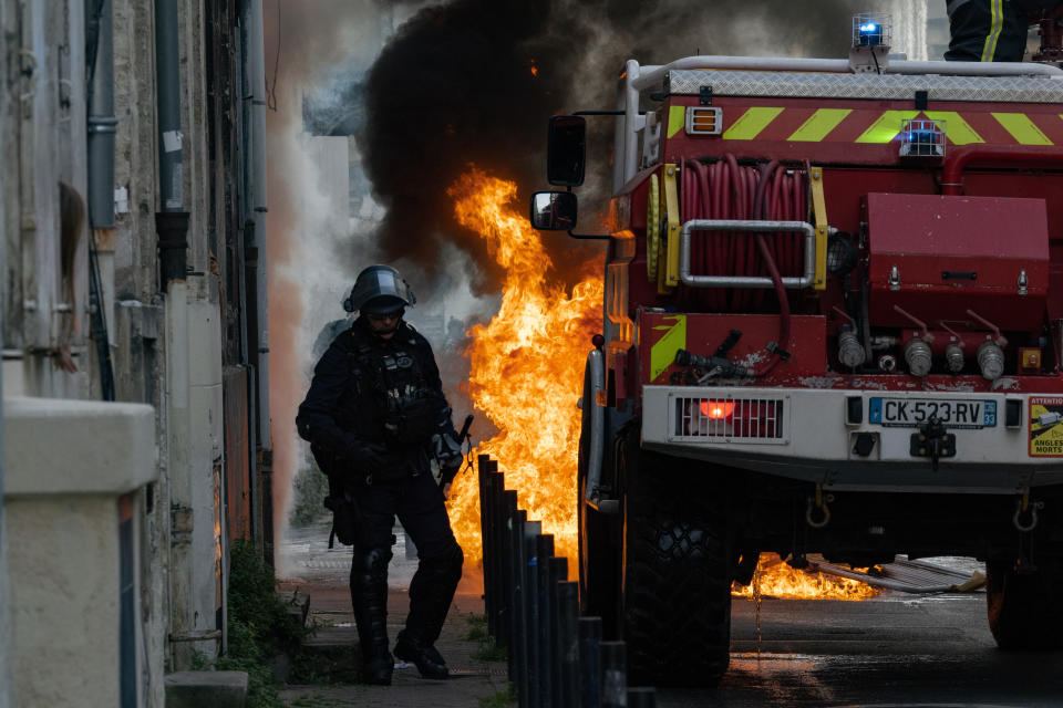 Anti-riot police officer passing by a fire in a demonstration on a national action day, a week after the government pushed a pensions reform through parliament without a vote, using the article 49.3 of the constitution, in Bordeaux, southwestern France, on March 23, 2023. French President defiantly vowed to push through a controversial pensions reform on March 22, 2023, saying he was prepared to accept unpopularity in the face of sometimes violent protests. (Photo by Jerome Gilles/NurPhoto via Getty Images)