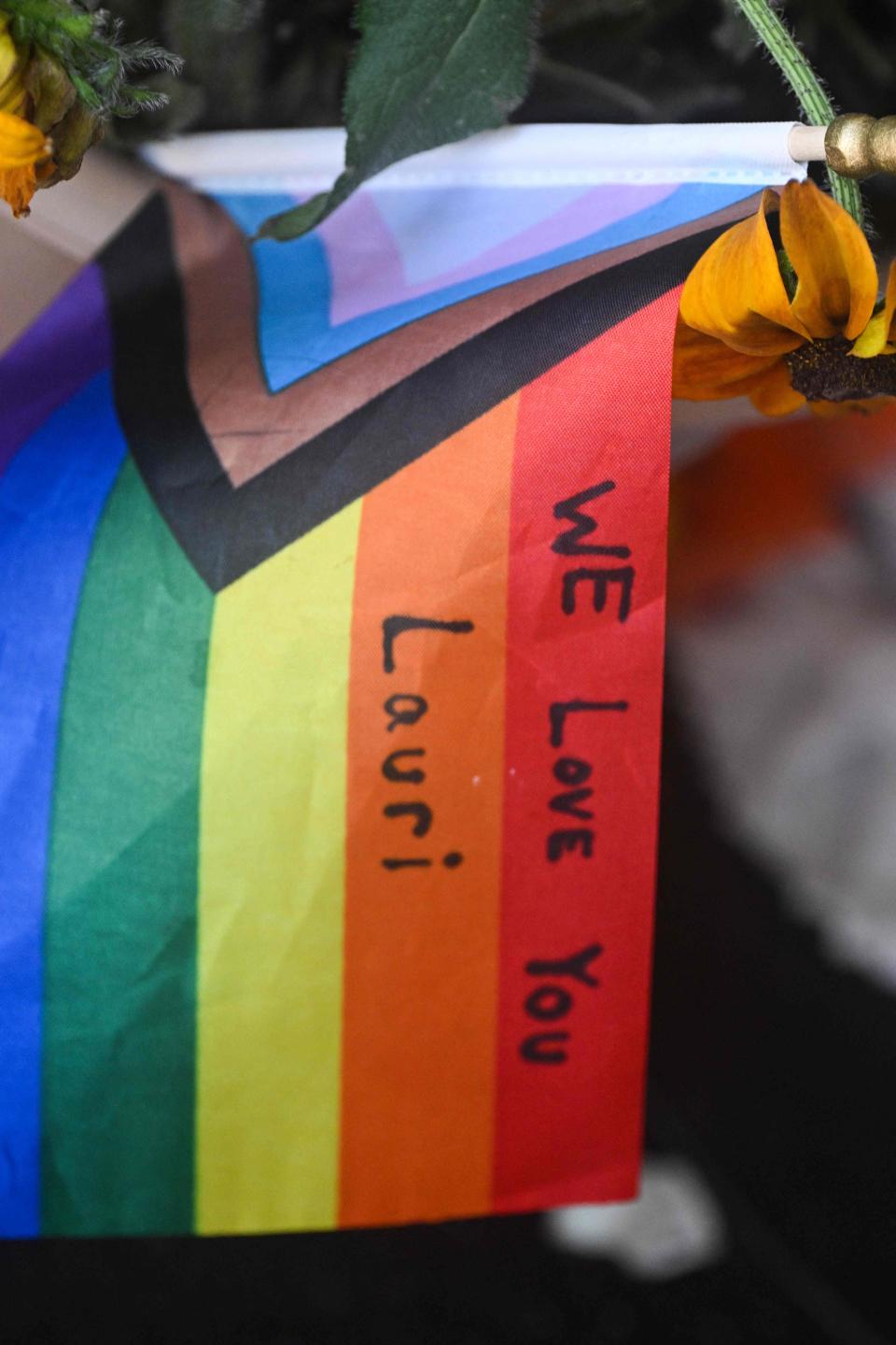 The message "We Love You Lauri " is seen on a Pride flag at a makeshift memorial outside the Mag.Pi clothing store in Cedar Glen, near Lake Arrowhead, California, on Aug. 21, 2023. The owner of the store, Laura Ann Carleton, was fatally shot on Aug. 18 by a man who "made several disparaging remarks about a rainbow flag" displayed outside her store, according to the San Bernardino County Sheriff's department. The suspect was later killed during an encounter with deputies.