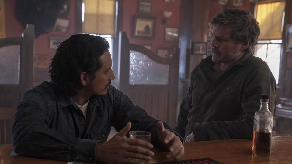 Gabriel Luna as Tommy and Pedro Pascal as Joel talk at a bar on The Last of Us