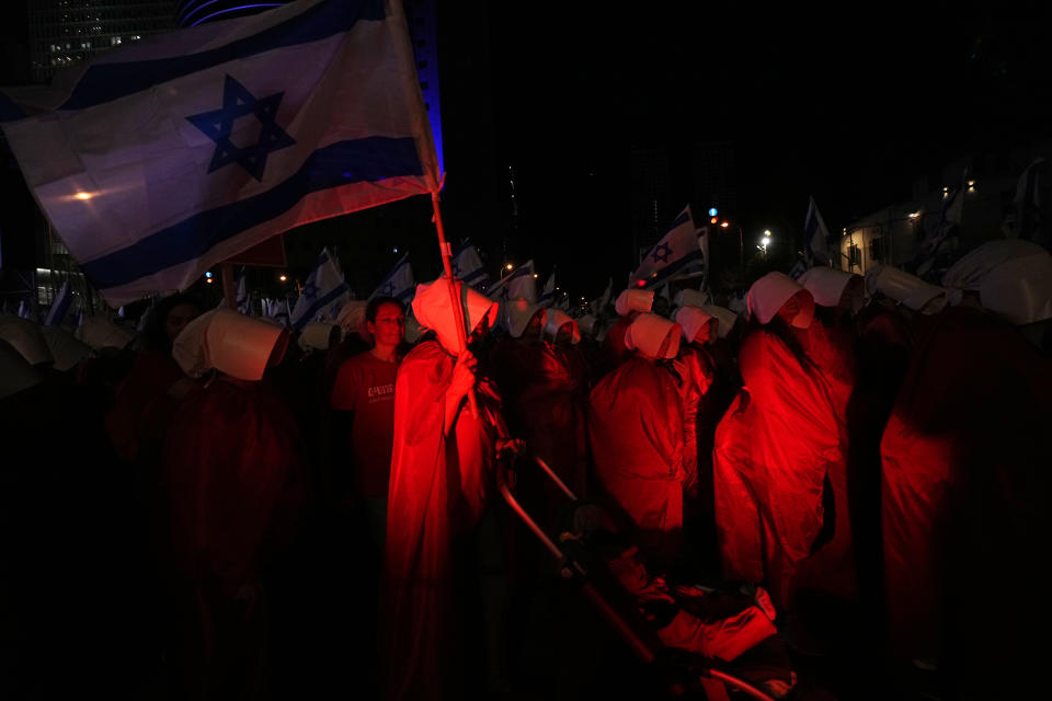 Israeli women's rights activists dressed as characters in the popular television series, "The Handmaid's Tale," protest plans by Prime Minister Benjamin Netanyahu's government to overhaul the judicial system, in Tel Aviv, Israel, Saturday, March 11, 2023. (AP Photo/Ohad Zwigenberg)