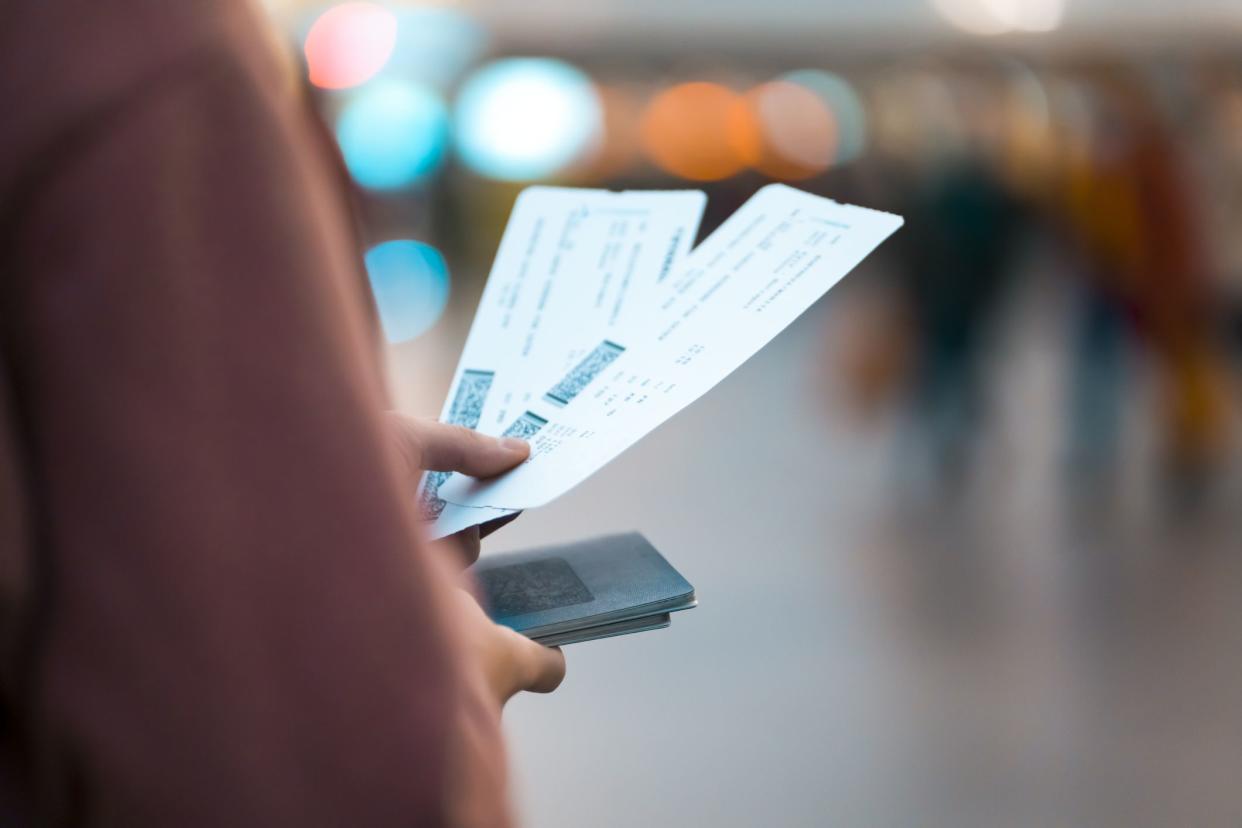 A young girl is going on a trip, holds plane tickets in her hands and goes to check-in, boarding a flight, close-up view of a boarding pass on a blurred background.