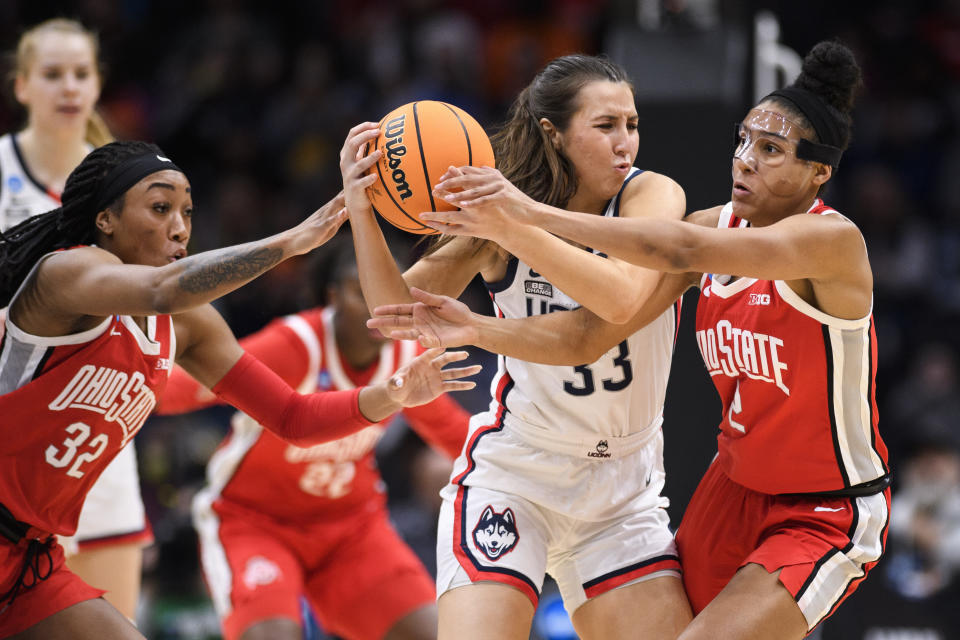 UConn guard Caroline Ducharme (33) holds onto the ball as Ohio State's Cotie McMahon (32) and Taylor Thierry (2) attempt to steal possession during the second quarter of a Sweet 16 college basketball game of the NCAA Tournament in Seattle, Saturday, March 25, 2023. (AP Photo/Caean Couto)