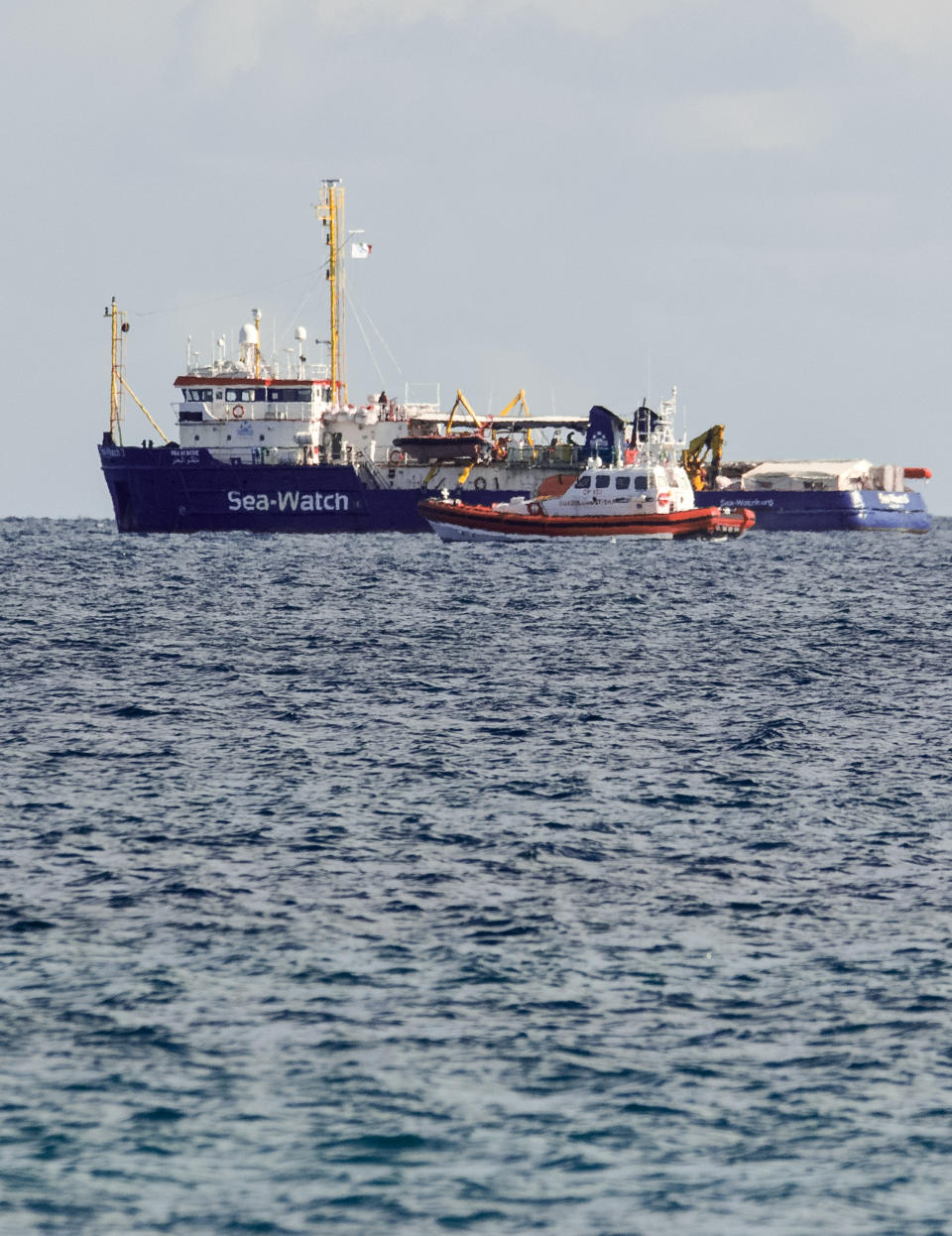 An Italian Coast Guard patroller flanks the Sea-Watch rescue ship off the Sicilian coast where it found shelter, about one nautical mile from Siracusa, from gale winds sweeping the Sicilian Channel, Friday, Jan. 25, 2019. The Sea-Watch is carrying 47 people saved from the sea. Italian Interior minister Salvini yesterday tweeted that the government is "ready to send food, medicine and whatever may be needed, but Italy's ports are and will remain closed". (AP Photo/Salvatore Cavalli)