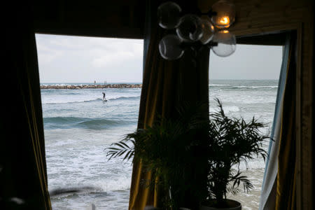 A surfer on a paddleboard is seen through the window of lifeguard tower which was renovated into a luxury hotel suite as part of an international online competition, at Frishman Beach in Tel Aviv, Israel March 14, 2017. REUTERS/Baz Ratner