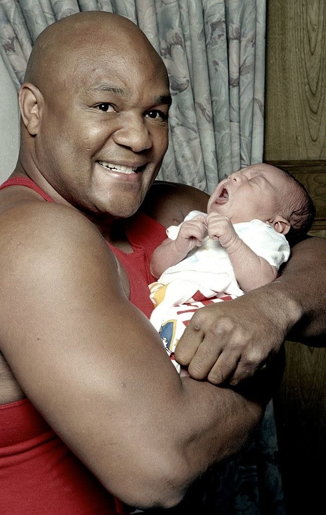 A smiling George holding a baby