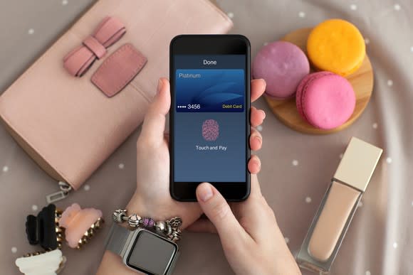 Hands holding a phone displaying the Apple pay concept.