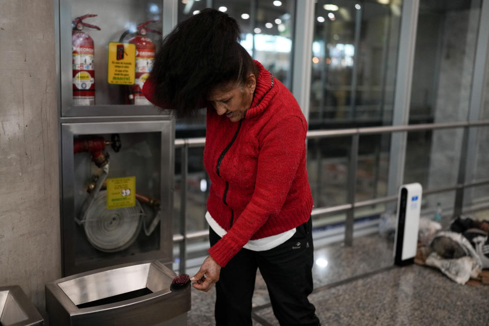 Mirta Lanuara, who is homeless, combs her hair inside the Jorge Newbery international airport, commonly known as Aeroparque, in Buenos Aires, Argentina, Thursday, April 6, 2023. Lanuara is one of over 100 homeless people who sleep at Aeroparque each night. (AP Photo/Natacha Pisarenko)