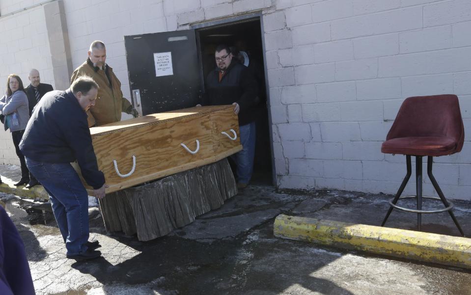 Mourners prepare to bring Jimmy Lehr's casket to a hearse at the All Around Bar in Taylor, Mich. on Thursday, Feb. 13, 2014. The suburban Detroit bar fulfilled the wish of their longtime employee who asked that his funeral be held at the watering hole where he worked for about 25 years. The 58-year-old died Feb. 7 after having pulmonary disease and congestive heart failure. A pine casket built at the bar was surrounded by flowers on the dance floor during a Wednesday wake. It's the same floor where Lehr's fourth wedding was held in 1996. At right is a stool similar to the seat Lehr occupied while on duty at the bar. (AP Photo/Carlos Osorio)