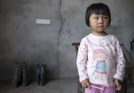 Two-year-old Xu Yilin, whose blood, according to her family, has been shown to have almost three times the national limit for lead exposure in children, stands in a neighbor's house in Dapu town, Hunan province, June 25, 2014. REUTERS/Alexandra Harney