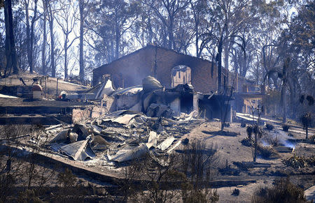 Smoke rises from a destroyed home after a bushfire swept through the town of Tathra, located on the south-east coast of New South Wales in Australia, March 19, 2018. AAP/Dean Lewins/via REUTERS