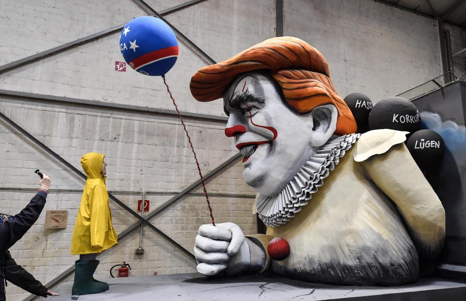 A man takes a picture of a satiric carnival float depicting US President Donald Trump as horror clown Pennywise during a preview in a hall in Cologne, Germany, Tuesday, Feb. 18, 2020. The traditional carnival parades on Rosemonday make fun of politics and are watched by hundreds of thousands in the streets of Cologne, Duesseldorf and Mainz. (AP Photo/Martin Meissner)