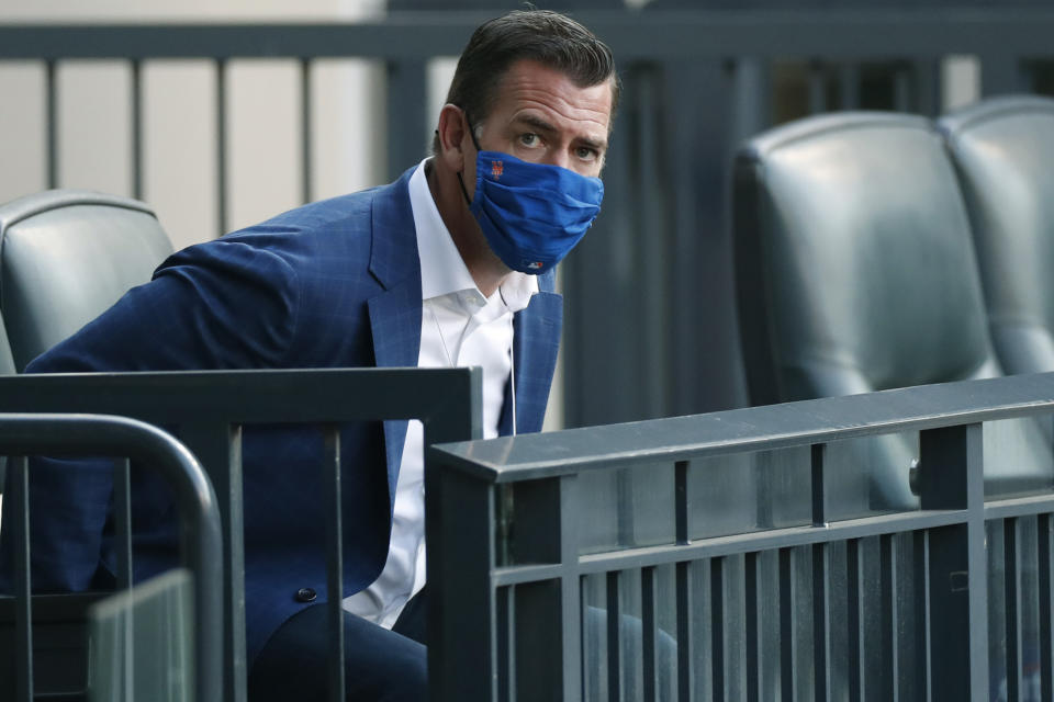 FILE- In this Aug. 10, 2020, file photo, New York Mets general manager Brodie Van Wagenen eyes a group of photographers as he takes a seat before a baseball game between the Mets and the Washington Nationals in New York. Van Wagenen and many of his top aides are out, moves announced less than an hour after hedge fund manager Steve Cohen completed his $2.4 billion purchase of the team Friday, Nov. 6, 2020. (AP Photo/Kathy Willens, File)