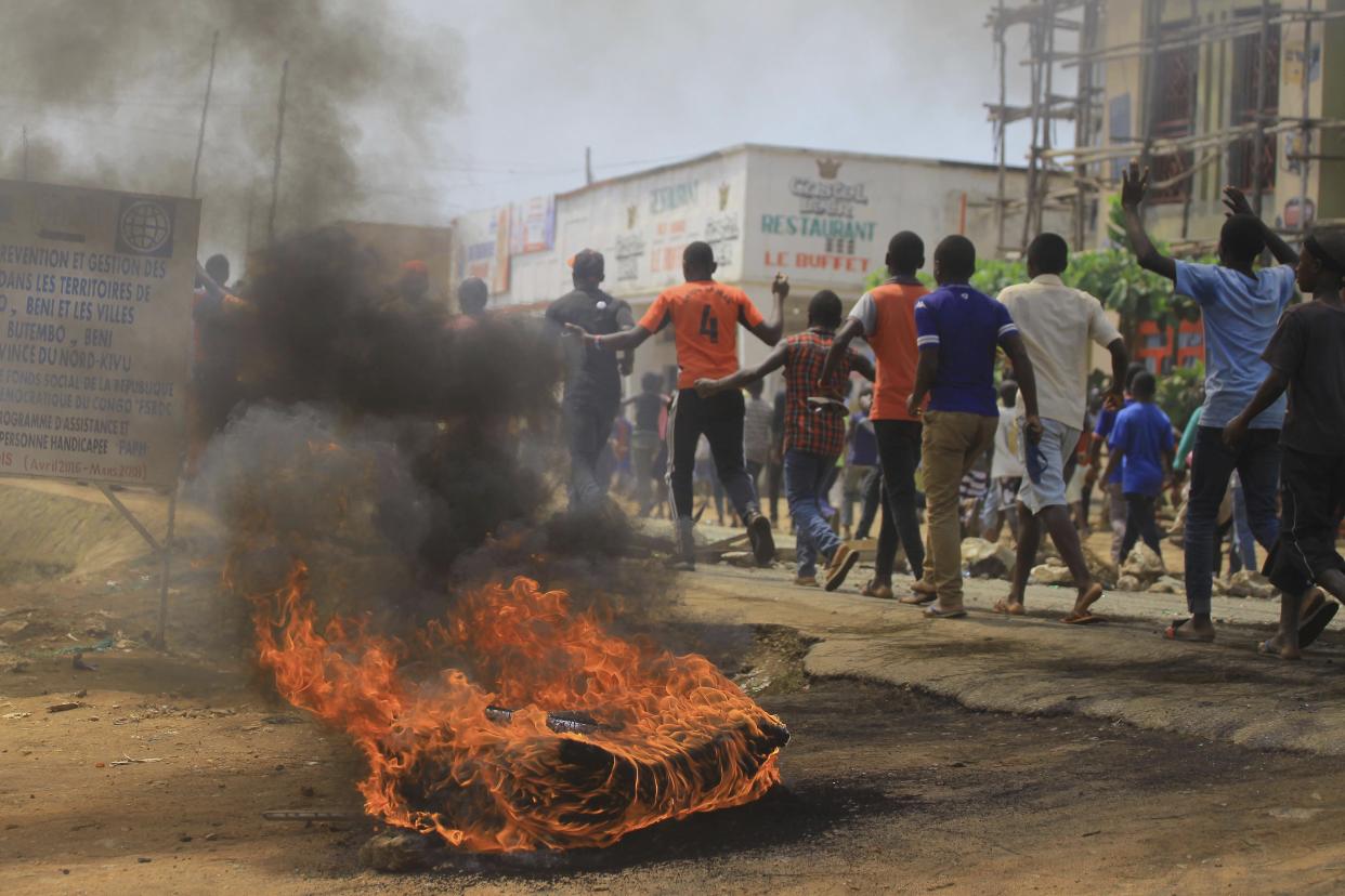 Protesters walk past a burning tire in Beni on Dec. 28, 2018, as they demonstrate against postponed voting in the Congolese election. (Photo: AP Photo/Al-hadji Kudra Maliro)